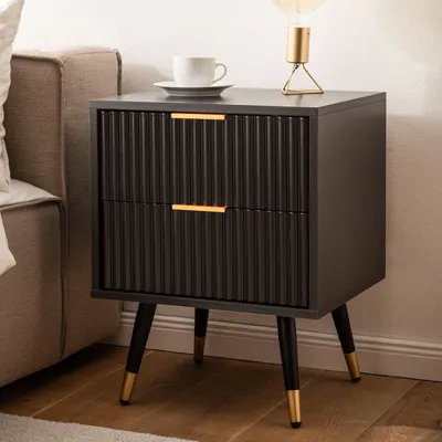 A modern black nightstand with gold accents is placed next to a sofa in a bedroom setting.