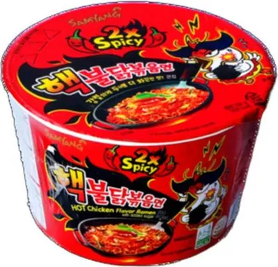 A close-up, slightly angled view of a red cup of Samyang 2x Spicy Buldak Ramyun instant noodles.