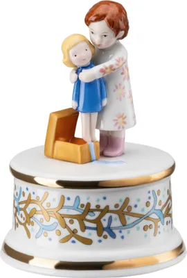 A porcelain music box with two figurines of children on top, one holding the other.