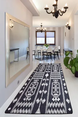 A hallway with a large mirror, a rug, and a dining area in the background.