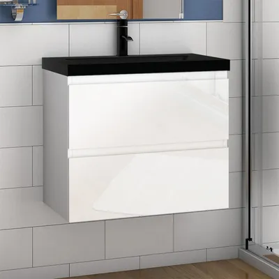 A modern white bathroom vanity with a black countertop and faucet, set against a tiled wall.