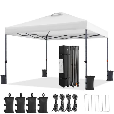 A white pop-up canopy tent is set up on a white surface, with its folded frame and accessories displayed nearby.