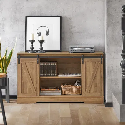 A wooden sideboard with sliding barn doors, decorated with books, a basket, and a record player, set against a textured gray wall.