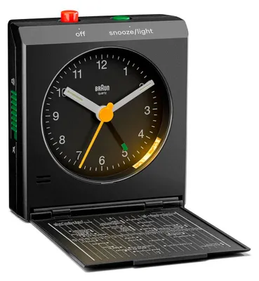 A black Braun alarm clock with its cover open, revealing a detailed chart inside.