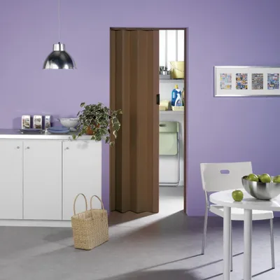 A room with a folding door, cabinets, a table with chairs, and a laundry area visible through the open door.