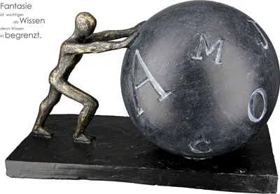 A decorative sculpture of a person pushing a large sphere with letters on it, placed on a black base.