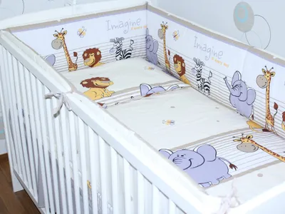 A baby crib with a safari-themed bumper pad.