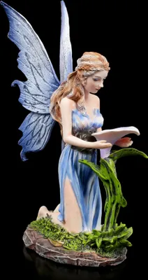 A figurine of a fairy kneeling next to a plant, holding a piece of paper.