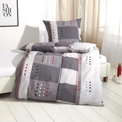 A neatly made bed with a grey, white, and red patterned duvet and pillow.