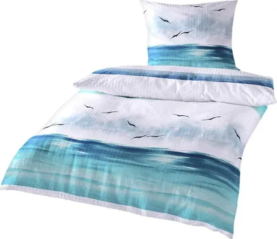 A bedding set with a coastal theme, featuring a watercolor-like print of the ocean and seagulls.