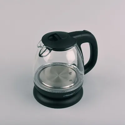 A glass electric kettle with a black lid and handle sits on a black base against a light gray background.