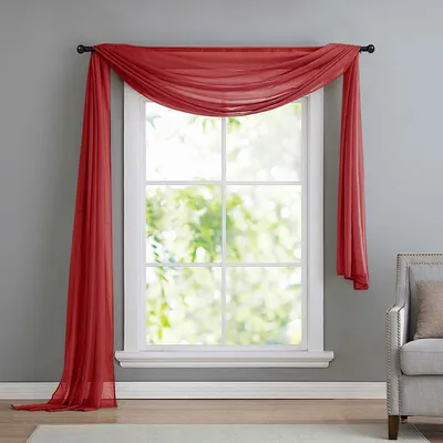 A red sheer scarf draped over a window.