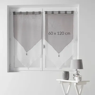 A window with two short curtains hanging, a small table with a lamp and a decorative pot.