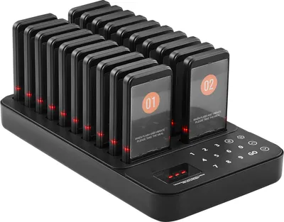 A black charging base with multiple pagers docked in it, displaying numbers and text.