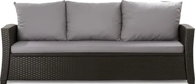 A studio shot of a dark brown rattan sofa with three gray cushions.