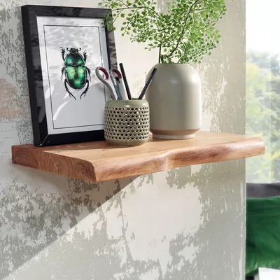 A wooden shelf mounted on a textured wall, decorated with a framed picture of a beetle, a pen holder with writing utensils, and a vase with a plant.