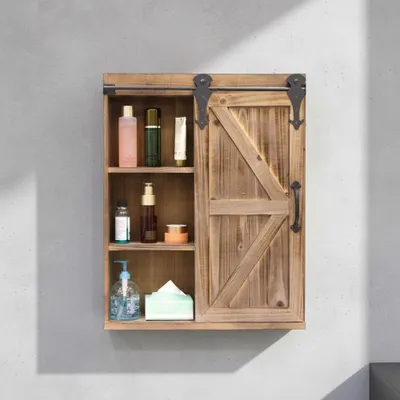 A wooden wall cabinet with a sliding barn door, displaying various toiletries and a tissue box on its shelves.
