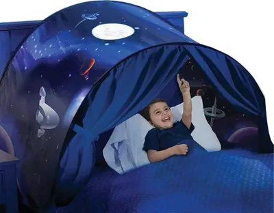 A young boy lies in bed inside a tent with a space-themed design.