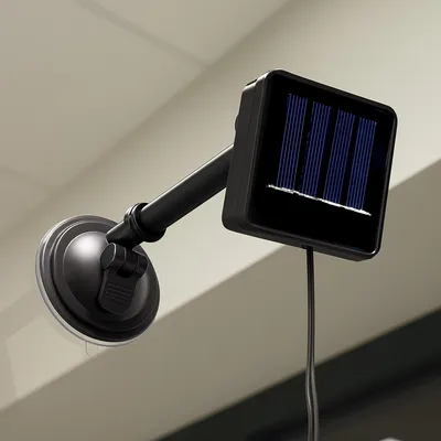 A solar-powered LED light fixture with a suction cup mount is shown attached to a surface, likely a window or wall.