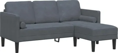 A dark gray sectional sofa with two small cylindrical pillows is shown against a white background.