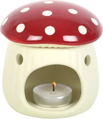 A ceramic oil burner shaped like a mushroom with a lit candle inside.