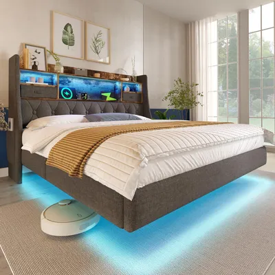 A modern bedroom with a grey upholstered bed frame featuring integrated LED lighting and storage shelves in the headboard. A robot vacuum cleaner is visible underneath the bed.