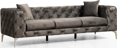 A gray tufted sofa with silver legs and two pillows.