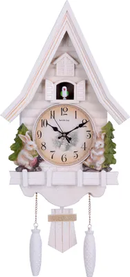 A decorative cuckoo clock with a house-like structure, featuring two rabbits and trees on either side of the clock face. A small bird is visible in a window above the clock.