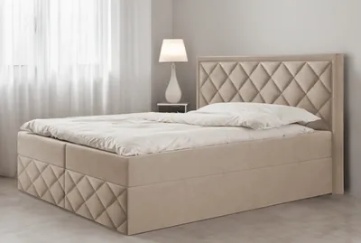 A beige upholstered bed with a diamond-stitched headboard and base, set in a softly lit bedroom with sheer curtains in the background.