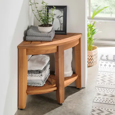 A wooden corner shelf unit with folded towels and a potted plant.