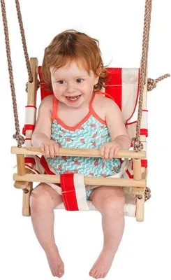 A young child is sitting in a wooden baby swing with red and white striped fabric.
