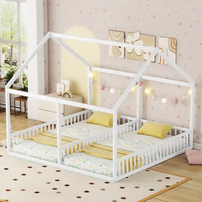 A white house-shaped twin bed frame with two mattresses, yellow pillows, and decorative string lights.