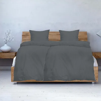 A bed with grey seersucker bedding and two pillows.
