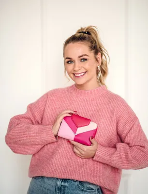 A woman is holding a pink wallet.