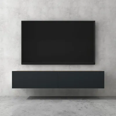 A wall-mounted TV and a lowboard cabinet against a concrete wall.