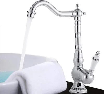 A chrome faucet with a white handle is shown with water flowing into a white sink, which has a white towel draped over its edge.