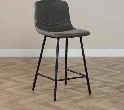 A bar stool is shown in a room with wooden flooring and a light-colored wall.