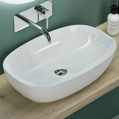 A white ceramic sink with a chrome faucet is shown on a wooden countertop against a green wall.