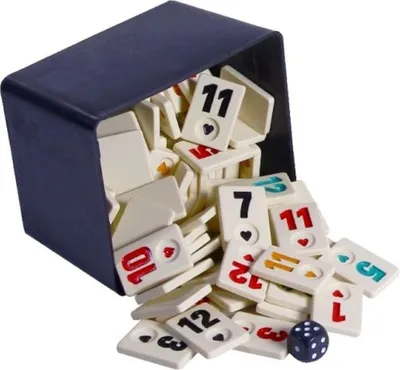 A dark blue box tipped over, spilling out many Rummy tiles and one die.