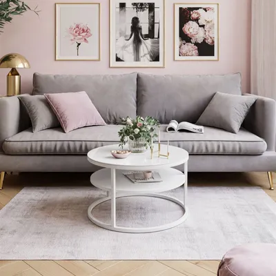 A living room scene with a gray sofa, a white coffee table, and artwork on a pink wall.