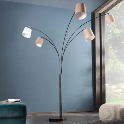 A multi-headed floor lamp with fabric shades stands in a room with a blue wall and a window.
