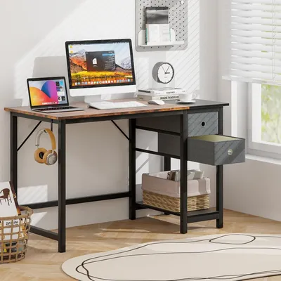A home office desk setup with a computer, laptop, headphones, and storage baskets.