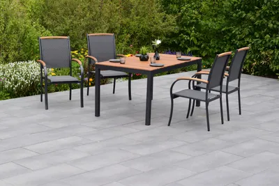 An outdoor dining set on a patio with greenery in the background.