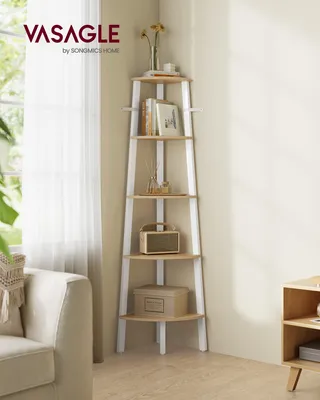 A corner shelf unit with decorations in a room next to a window and a couch.