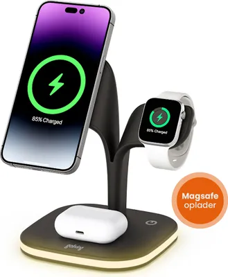 A black and silver 5-in-1 wireless charging station is shown with a smartphone, smartwatch, and earbuds charging on it. The charging station has a subtle yellow light around its base.