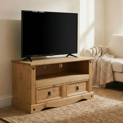 A TV stand with a TV on top, in a living room setting with a sofa and blanket in the background.