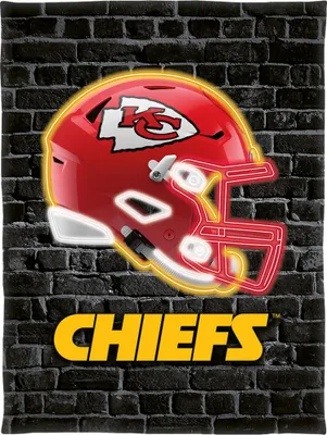 A Kansas City Chiefs helmet and team name displayed against a brick wall.
