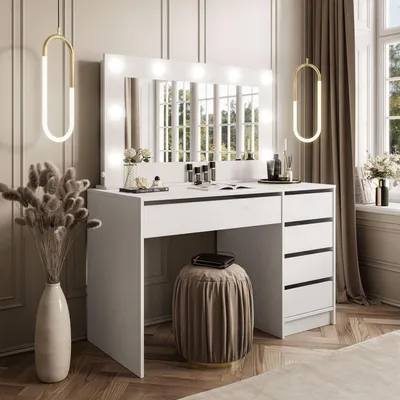 A white vanity table with a lighted mirror, drawers, and a stool, set in a well-lit room with decorative elements.