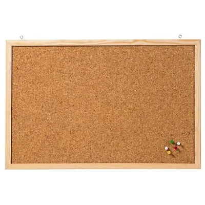 A cork board with a wooden frame, hanging from two hooks. Several push pins are visible in the bottom right corner.
