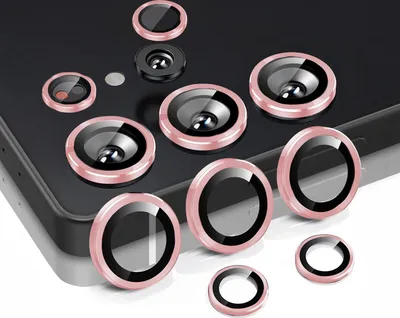 A collection of camera lens protectors with pink rims arranged on a dark surface.